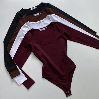 A collection of four deep scoop neck long-sleeve bodysuits in black, white, burgundy, and brown colors, laid out flat from Laconic Fashion Nepal 