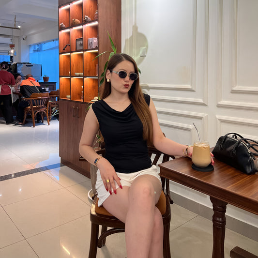 A woman wearing a black sleeveless top called Grace Cowl Neck detail Sleeveless Top that is trending in Nepal right now. The best Cowl Neck Sleeveless Top in Nepal by Laconic Fashion Nepal. Classic yet luxury wear and affordable pricing